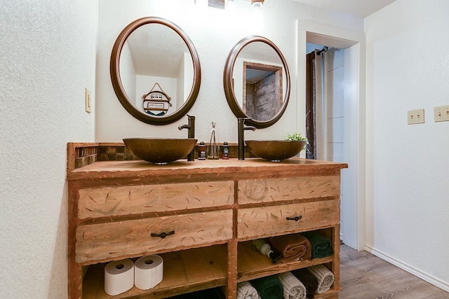 bathroom with wood finished floors, a textured wall, and a sink