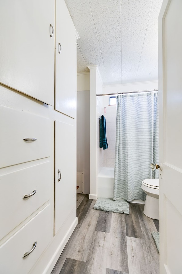 full bath featuring toilet, shower / bathtub combination with curtain, and wood finished floors