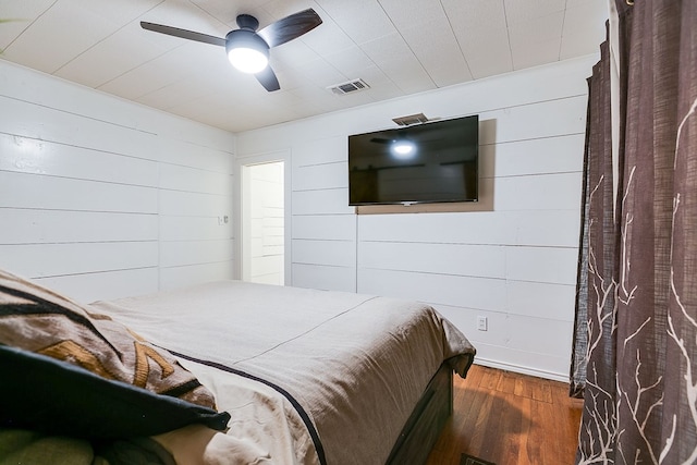 bedroom featuring wood finished floors, a ceiling fan, visible vents, and baseboards