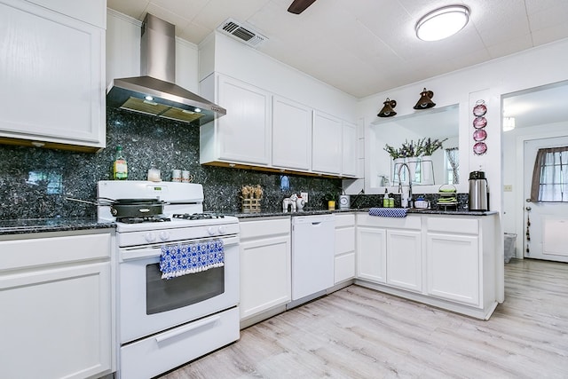 kitchen with visible vents, white appliances, wall chimney range hood, a sink, and light wood-type flooring
