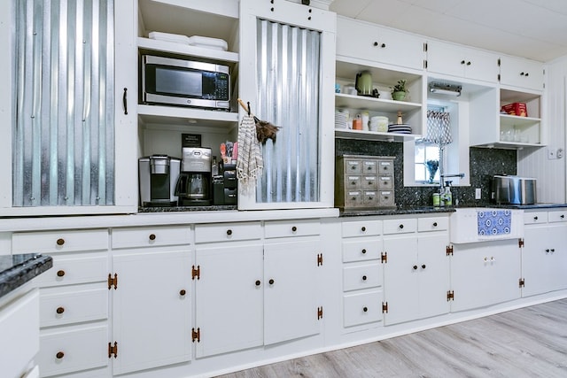 kitchen with tasteful backsplash, white cabinets, open shelves, and stainless steel microwave