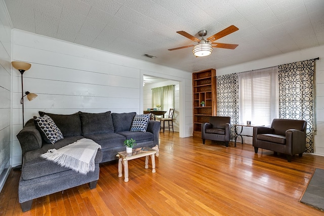 living area with visible vents, a ceiling fan, and wood-type flooring