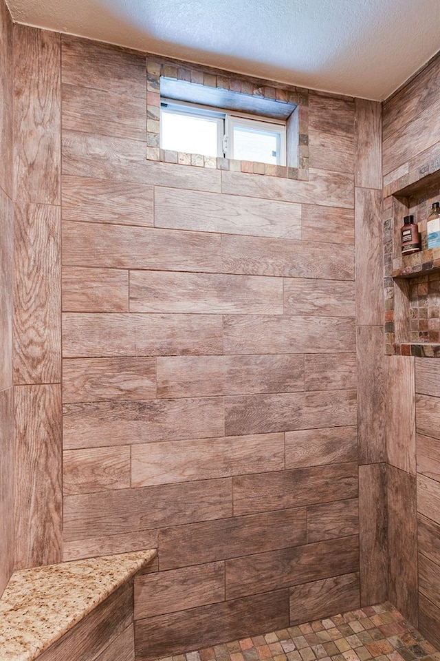 bathroom featuring a tile shower and a textured ceiling