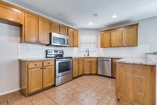 kitchen featuring stainless steel appliances, light stone countertops, sink, and a textured ceiling