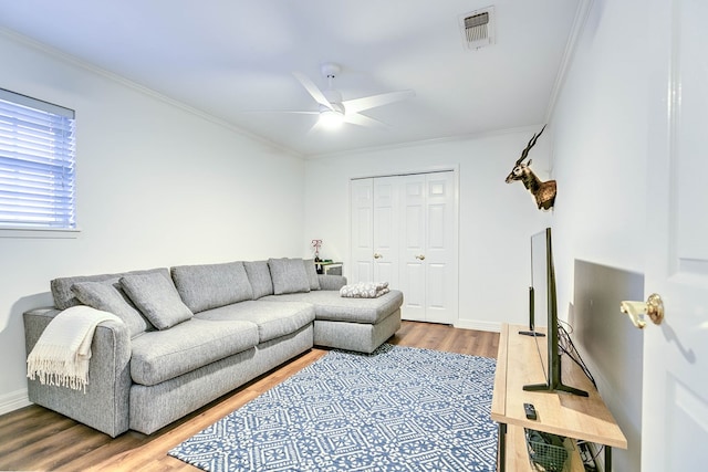 living room featuring wood finished floors, a ceiling fan, ornamental molding, and baseboards