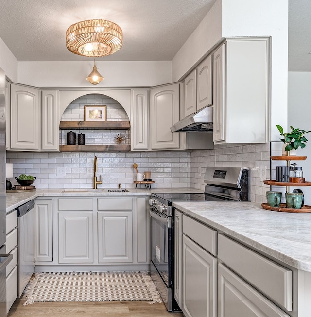 1702 Parkview Dr, San Angelo, TX 76904 - kitchen with stainless steel appliances, under cabinet range hood, a sink, light wood-type flooring, and backsplash