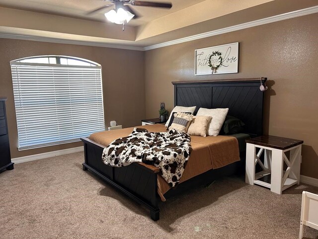 carpeted bedroom featuring a raised ceiling, ornamental molding, and ceiling fan