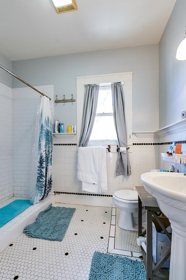 bathroom with tile patterned flooring, toilet, tile walls, and a shower with shower curtain