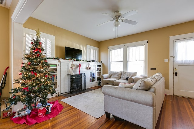 living room featuring dark hardwood / wood-style flooring, ceiling fan, and a wood stove