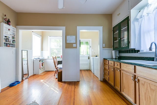 kitchen featuring separate washer and dryer, sink, and light hardwood / wood-style flooring