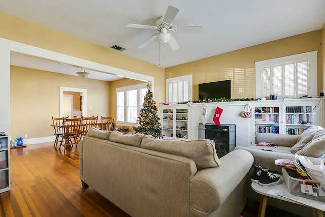 living room featuring wood-type flooring, ceiling fan, and a fireplace