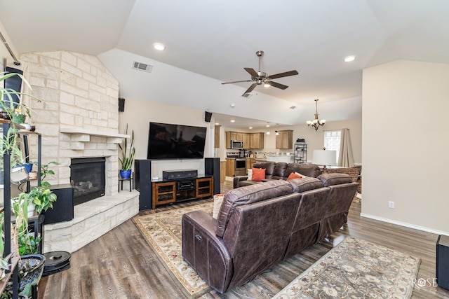 living room featuring a fireplace, hardwood / wood-style flooring, vaulted ceiling, and ceiling fan with notable chandelier