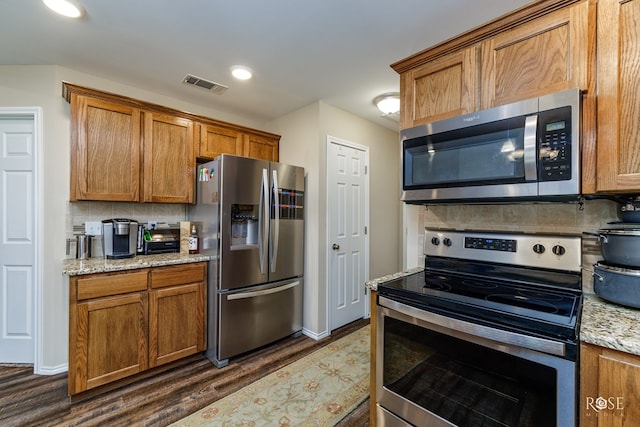 kitchen featuring tasteful backsplash, appliances with stainless steel finishes, dark hardwood / wood-style floors, and light stone counters