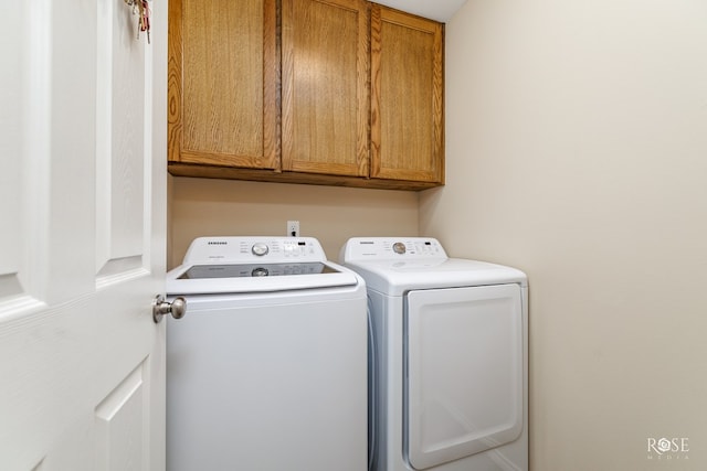 clothes washing area with cabinets and washer and clothes dryer