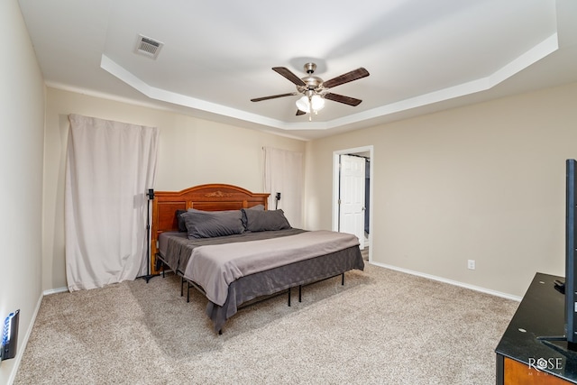 carpeted bedroom featuring ceiling fan and a tray ceiling