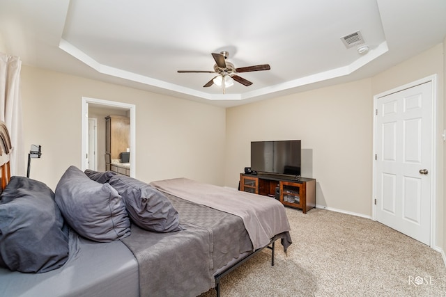 carpeted bedroom with ceiling fan and a raised ceiling