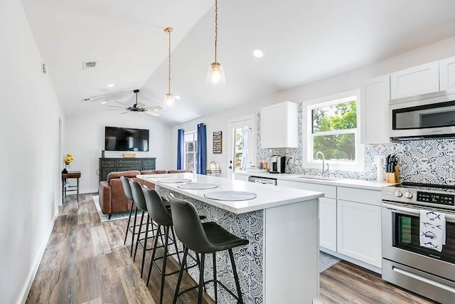 kitchen with a sink, tasteful backsplash, visible vents, a kitchen island, and appliances with stainless steel finishes