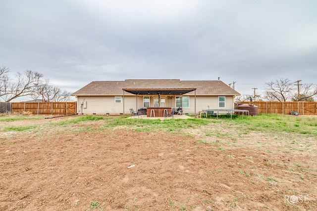 back of property with a fenced backyard, a patio area, a jacuzzi, and a trampoline