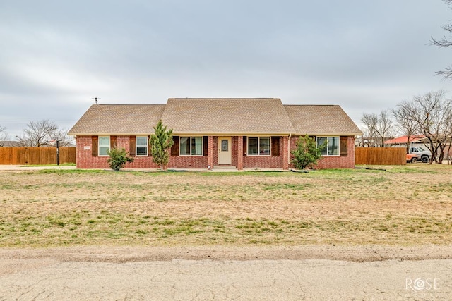 ranch-style house with brick siding, roof with shingles, and fence