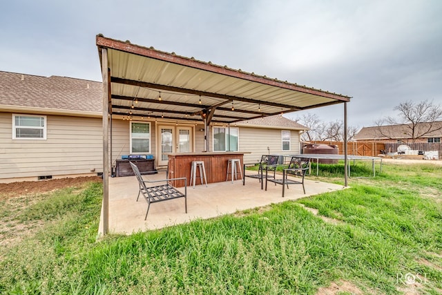 back of house with outdoor dry bar, a patio, a trampoline, fence, and crawl space