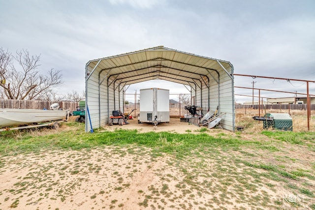 view of outdoor structure with a carport and fence