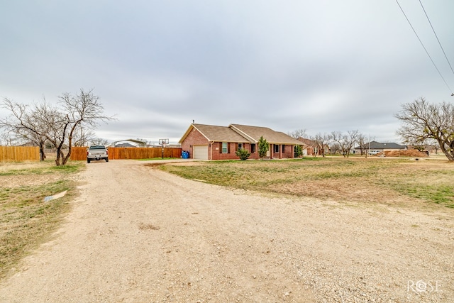 view of front of house featuring brick siding, driveway, an attached garage, and fence