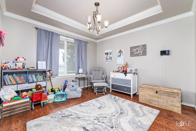 game room with a tray ceiling, wood finished floors, a chandelier, and crown molding