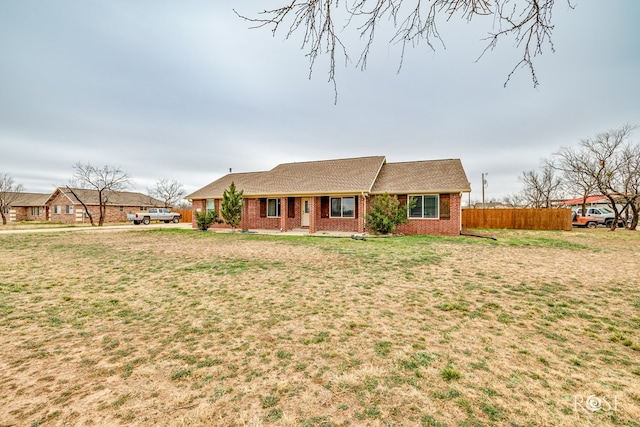 ranch-style home with a front yard, fence, and brick siding