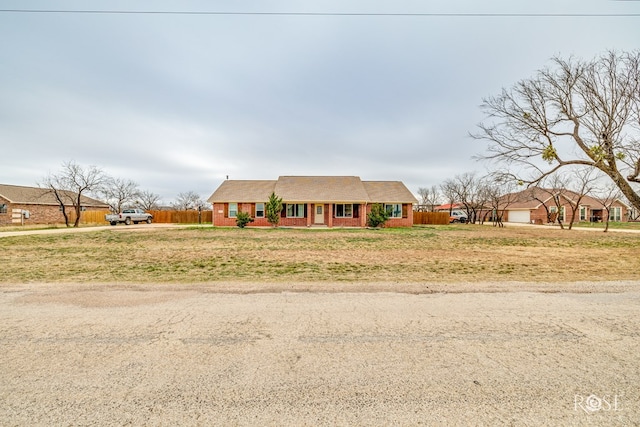 view of front of house featuring brick siding, a front yard, a garage, and fence