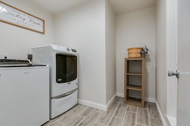 washroom with washing machine and dryer, laundry area, baseboards, and wood finish floors