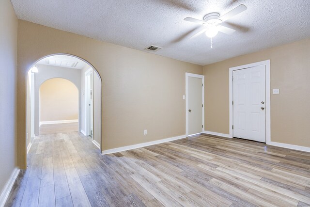 2813 Pecan St, San Angelo, TX 76903 - empty room with a ceiling fan, arched walkways, a textured ceiling, and light wood-style floors