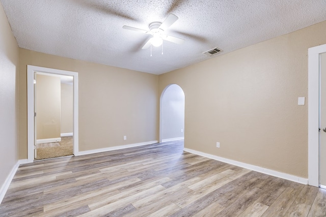 spare room with ceiling fan, light hardwood / wood-style flooring, and a textured ceiling