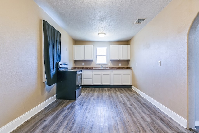 2813 Pecan St, San Angelo, TX 76903 - kitchen with stainless steel electric range, white cabinetry, a textured ceiling, wood finished floors, and dark countertops