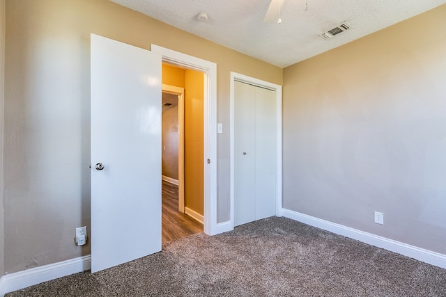 unfurnished bedroom featuring a closet, dark carpet, and a textured ceiling