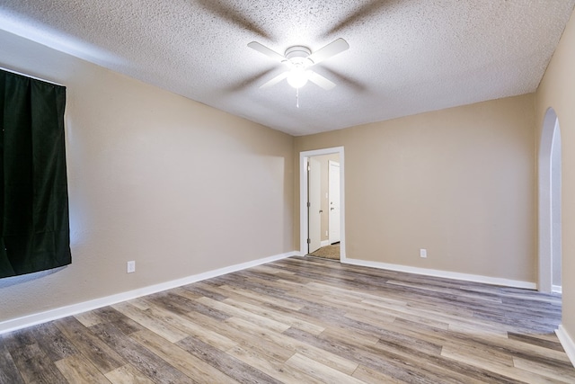 empty room with ceiling fan, a textured ceiling, and light wood-type flooring