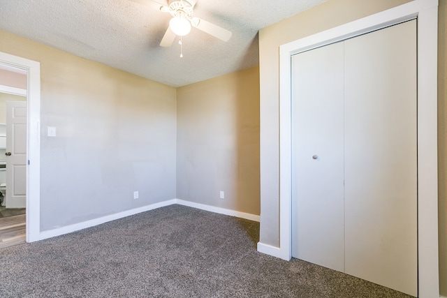unfurnished bedroom with a ceiling fan, a closet, a textured ceiling, baseboards, and dark carpet