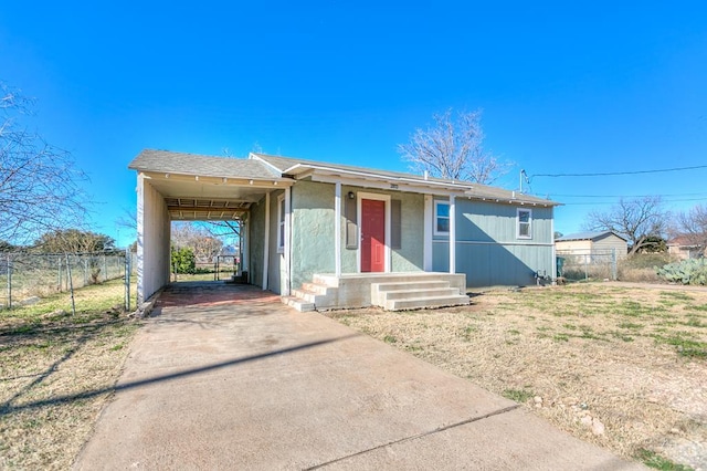 view of front facade with concrete driveway, fence, and a carport