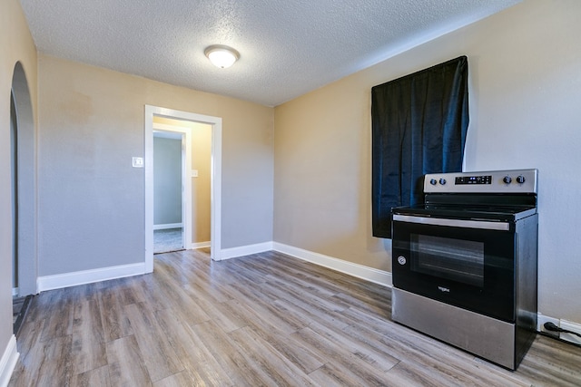 kitchen featuring electric stove, a textured ceiling, and light wood-type flooring