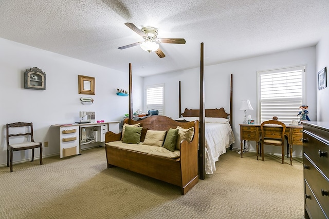 bedroom with ceiling fan, light carpet, and a textured ceiling