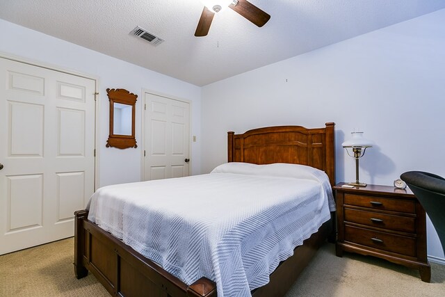 bedroom with light carpet, a textured ceiling, and ceiling fan