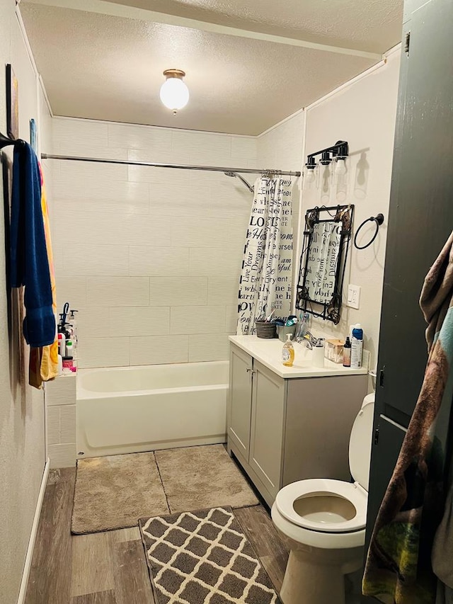 810 N 11th St, Junction, TX 76849 - bathroom featuring wood finished floors, toilet, vanity, a textured ceiling, and shower / bath combo with shower curtain