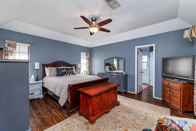 bedroom with vaulted ceiling, wood finished floors, visible vents, and baseboards