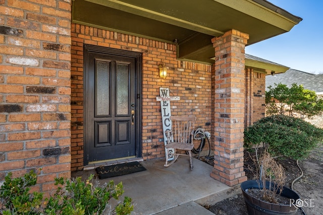 doorway to property featuring brick siding and a porch