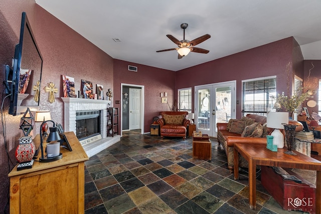 living room with french doors, stone tile floors, visible vents, a brick fireplace, and ceiling fan