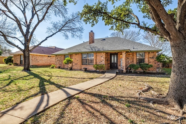 ranch-style house featuring a front yard, a shingled roof, a chimney, and brick siding