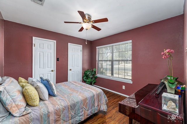 bedroom featuring baseboards, wood finished floors, visible vents, and a ceiling fan