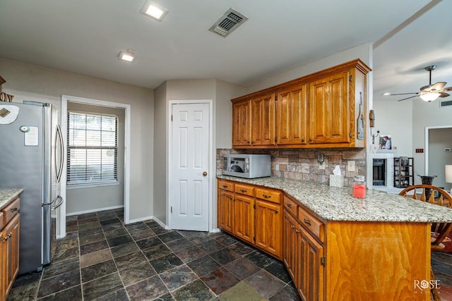 4917 Bermuda Dr, San Angelo, TX 76904 - kitchen featuring stainless steel appliances, baseboards, tasteful backsplash, and brown cabinets