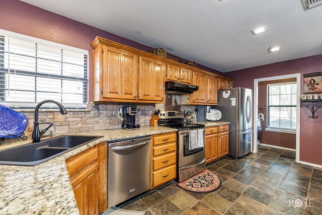 kitchen featuring under cabinet range hood, a sink, visible vents, appliances with stainless steel finishes, and backsplash