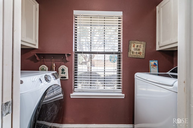 laundry area featuring a textured wall, washing machine and clothes dryer, and cabinet space