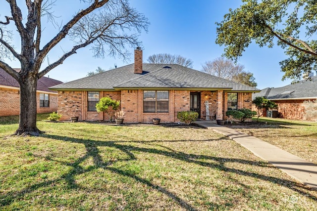 ranch-style house featuring a front yard, brick siding, a chimney, and roof with shingles